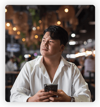 a man sitting in a restaurant looking pensive and holding his phone